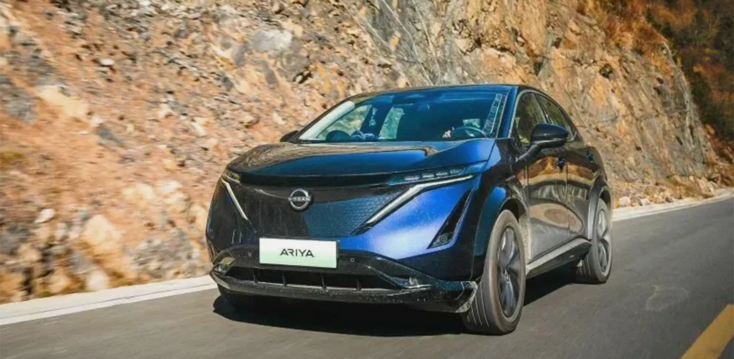 Blue Nissan Ariya driving fast on mountain road showcasing power and performance