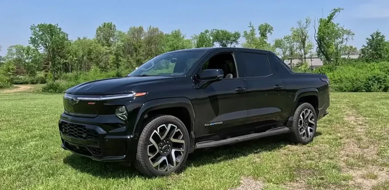 How to Charge Silverado EV: A black Silverado EV parked on a green grassy field with a forest in the background.