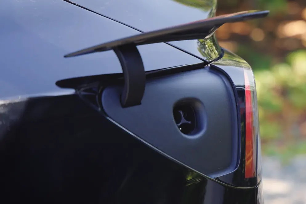 What is NACS Charging – Close-up of a Tesla electric vehicle’s NACS charging port under the rear spoiler, representing the North American Charging Standard.