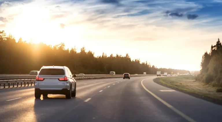Car driving on highway at sunset representing EV road trips with portable ev charger for road trips