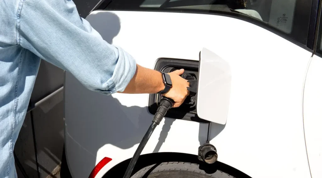 Person plugging a portable EV charger for road trips into an electric car