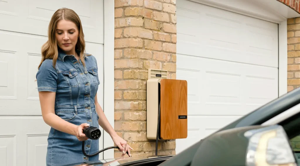 Woman plugging in an EV charger next to a garage using a smart Level 2 unit