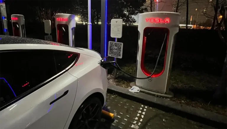 Tesla electric vehicle charging in the rain at a Supercharger station