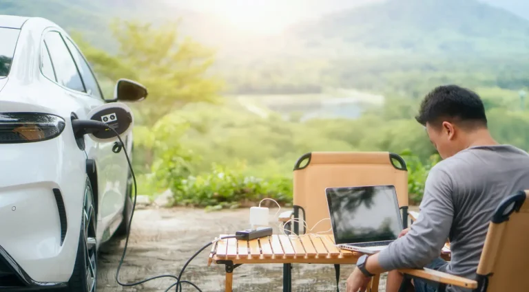 Electric car using Vehicle-to-Load (V2L) technology to power laptop during outdoor work
