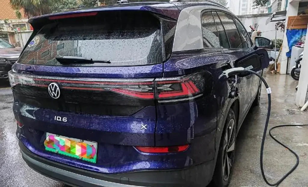 Volkswagen ID.6 electric SUV charging outdoors in rainy conditions