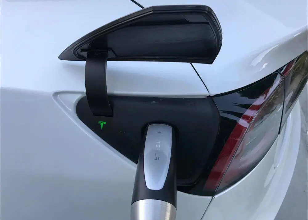 Close-up of a Tesla vehicle connected to a charger using the SAE J3400 connector