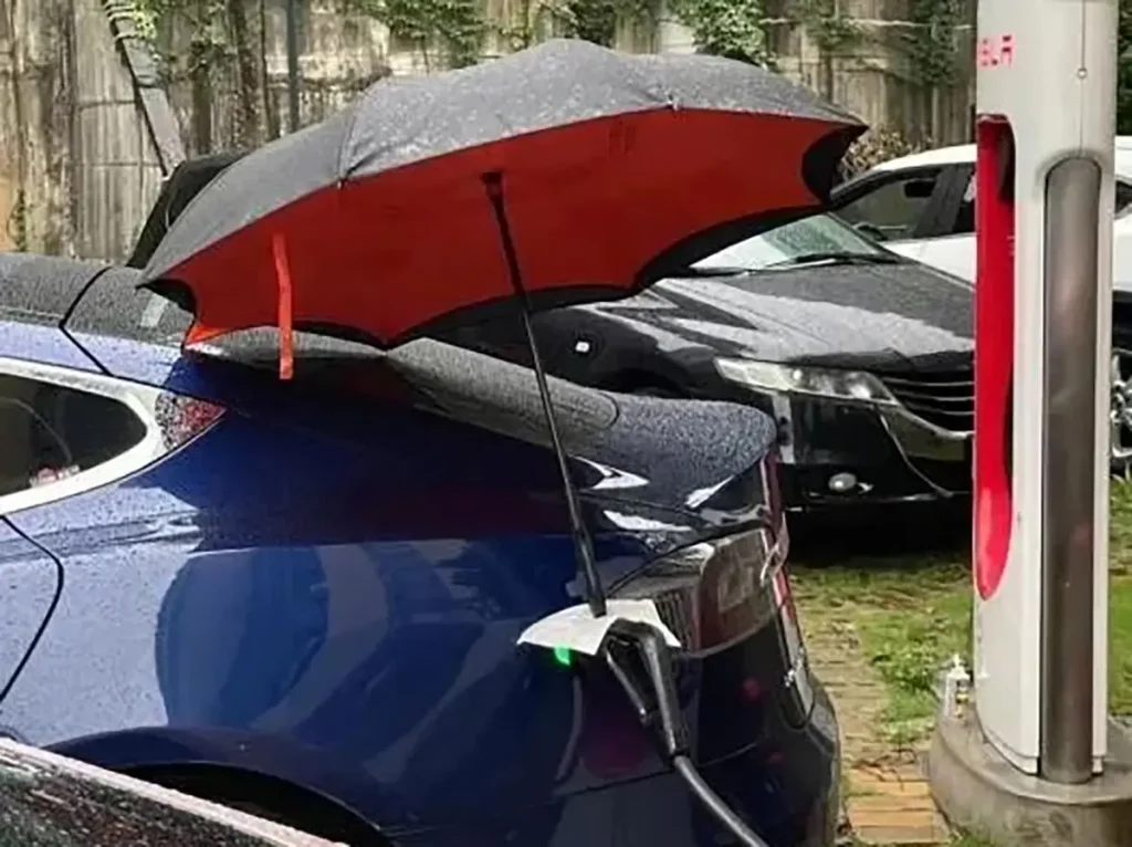 EV charging in the rain with an umbrella covering the charge port