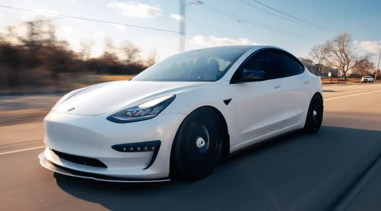 White Tesla driving on the road illustrating real-world Tesla battery lifespan