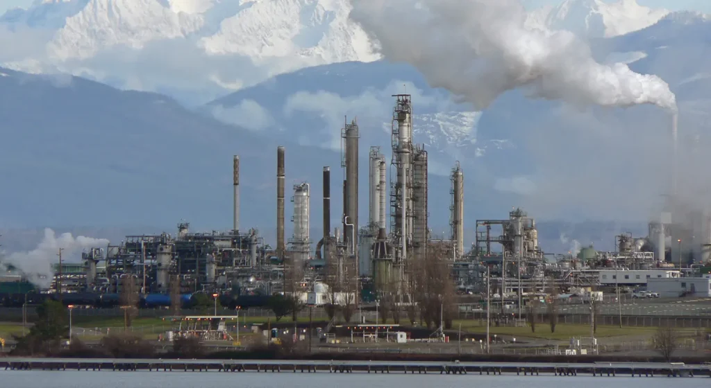 Oil refinery producing emissions during fuel extraction and refining before gasoline reaches vehicles.