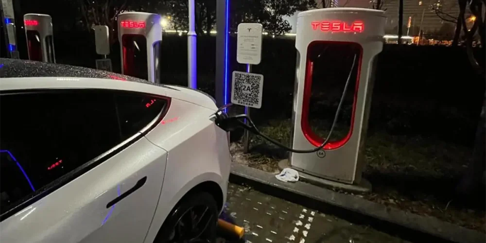 Tesla electric vehicle charging in the rain at a Supercharger station