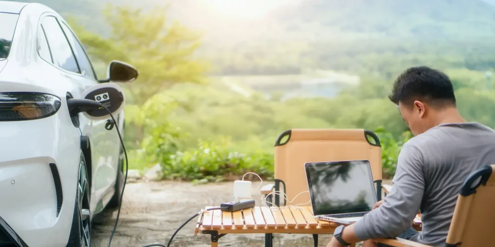 Electric car using Vehicle-to-Load (V2L) technology to power laptop during outdoor work