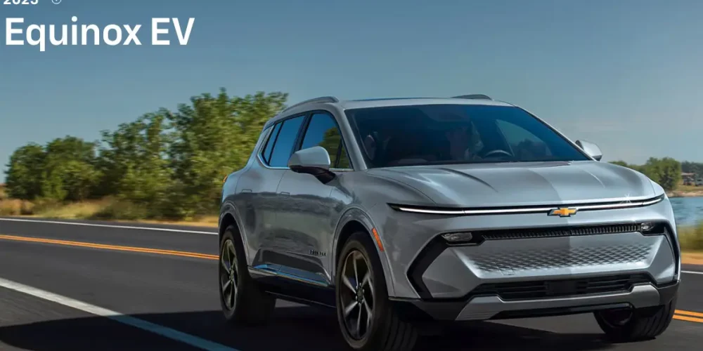 Front view of 2025 Chevy Equinox EV electric SUV driving on a highway under blue sky, demostrating chevy equinox ev charging importance to enhance its driving experience