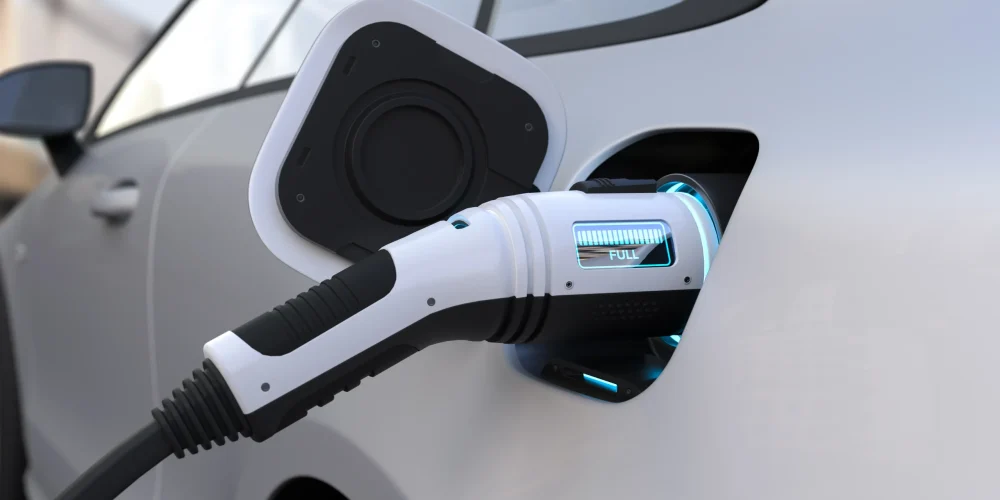 Tesla portable charger plugged into an electric vehicle showing full charge indicator